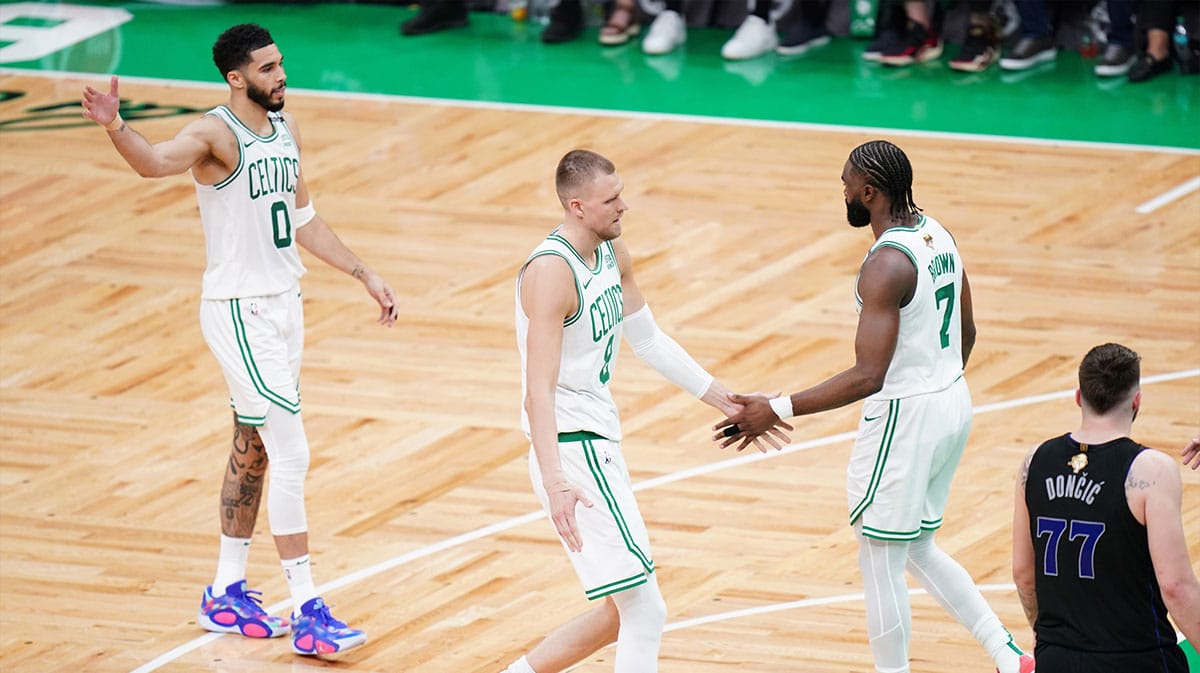 Boston Celtics center Kristaps Porzingis (8) and guard Jaylen Brown (7) and forward Jayson Tatum (0) react in the second quarter against the Dallas Mavericks during game one of the 2024 NBA Finals at TD Garden.